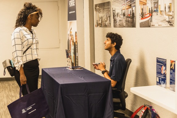 Student talking to another student behind a table